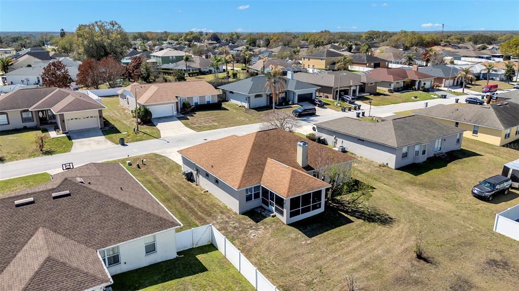 An aerial view shows several suburban houses with brown roofs and fenced backyards — 7755 CANTERBURY CIRCLE, LAKELAND, FL