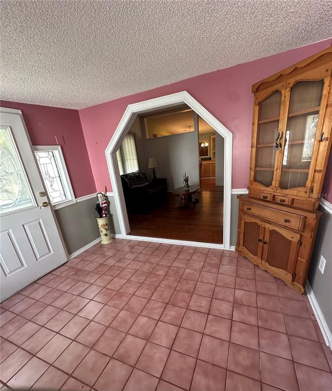 An entryway with pink walls, gray wainscoting, tiled floors, and a wooden hutch — 907 ORCHID STREET, LADY LAKE, FL