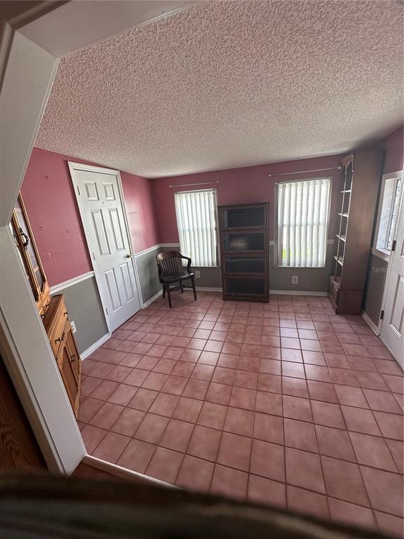 A room with pink walls, gray wainscoting, tile flooring, two windows with blinds, and furniture — 907 ORCHID STREET, LADY LAKE, FL