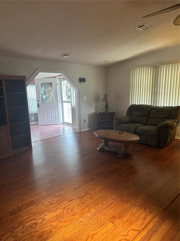 A living room features wood flooring, a brown loveseat, a coffee table, and an entryway — 907 ORCHID STREET, LADY LAKE, FL