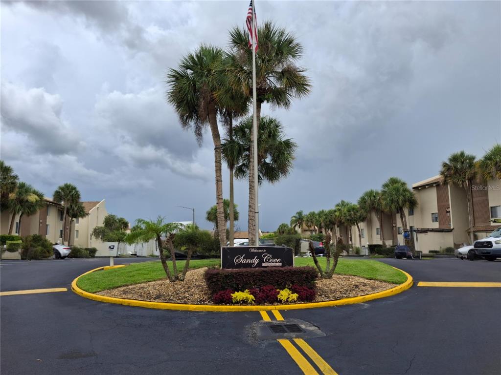 A sign for Sandy Cove stands in a circular driveway surrounded by palm trees — 622 ORANGE DRIVE UNIT 232, ALTAMONTE SPRINGS, FL