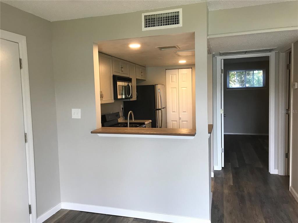 A kitchen with light cabinets and stainless appliances is viewed through a pass-through window — 622 ORANGE DRIVE UNIT 232, ALTAMONTE SPRINGS, FL