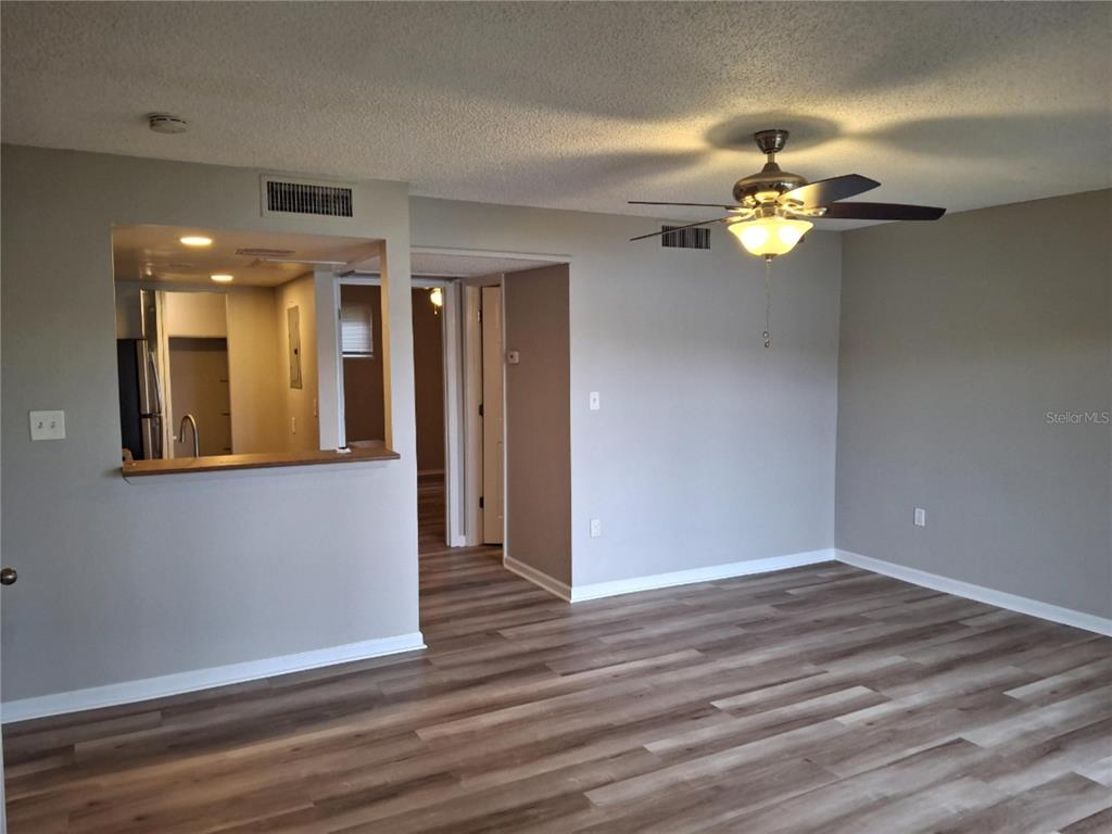 A living room with wood-look flooring, a ceiling fan, and an open pass-through to the kitchen — 622 ORANGE DRIVE UNIT 232, ALTAMONTE SPRINGS, FL