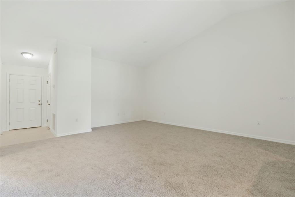 An empty room with white walls, beige carpeting, and a vaulted ceiling — 20 BUTTONWOOD LANE, PALM COAST, FL