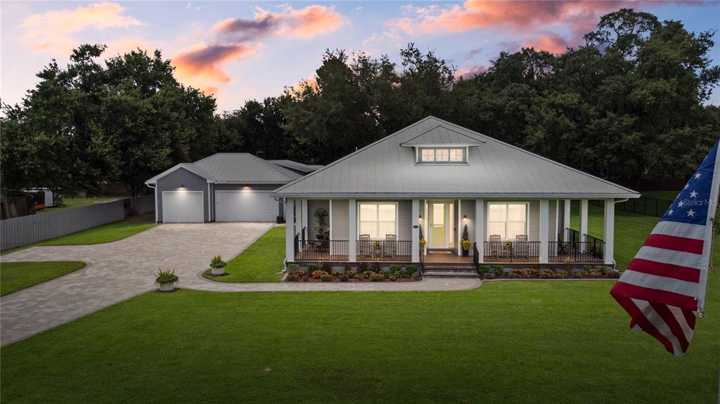 A single-story house with a metal roof, front porch, and detached garage at sunset — 4421 JIM BRANCH ROAD, KISSIMMEE, FL