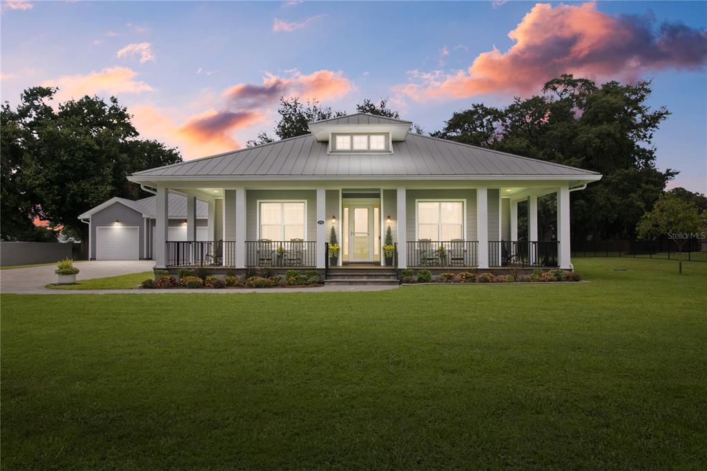 A single-story house with a metal roof, front porch, and detached garage at sunset — 4421 JIM BRANCH ROAD, KISSIMMEE, FL