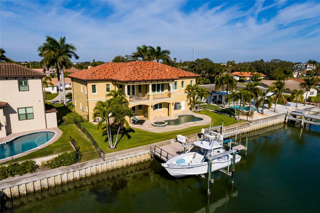 An aerial view of a waterfront house with a pool, lawn, and a docked boat — 1976 KANSAS AVENUE NE, ST PETERSBURG, FL
