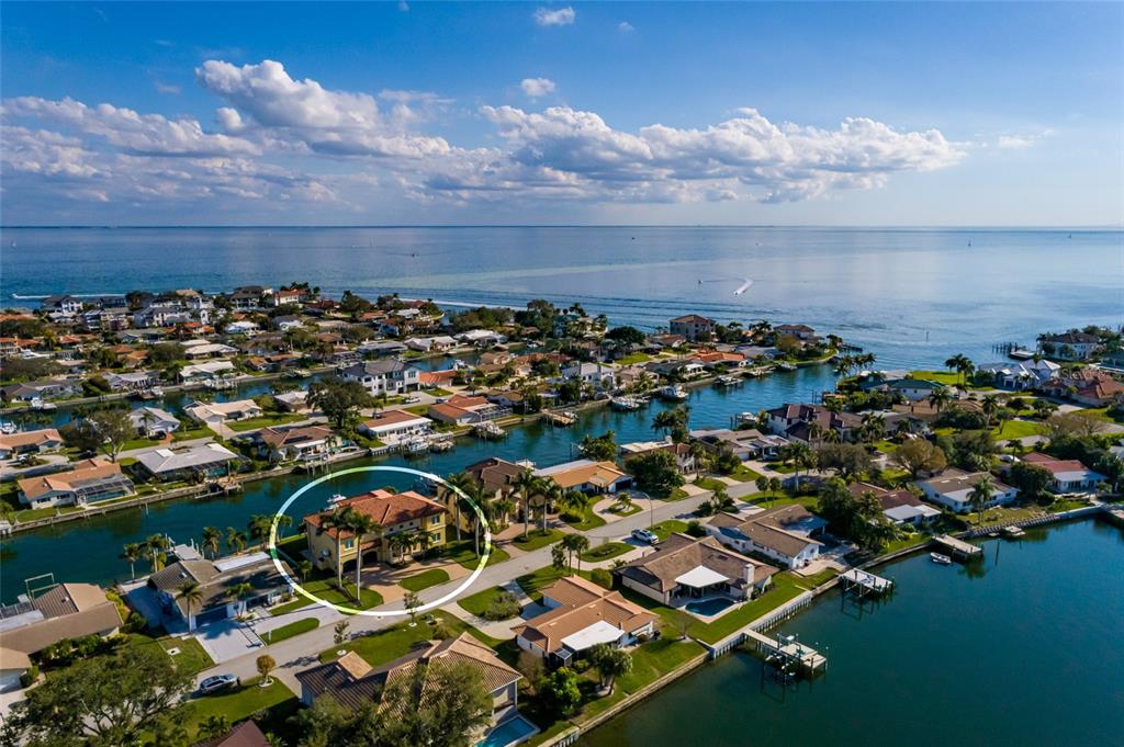 An aerial view shows a two-story house with a red-tiled roof near a canal — 1976 KANSAS AVENUE NE, ST PETERSBURG, FL