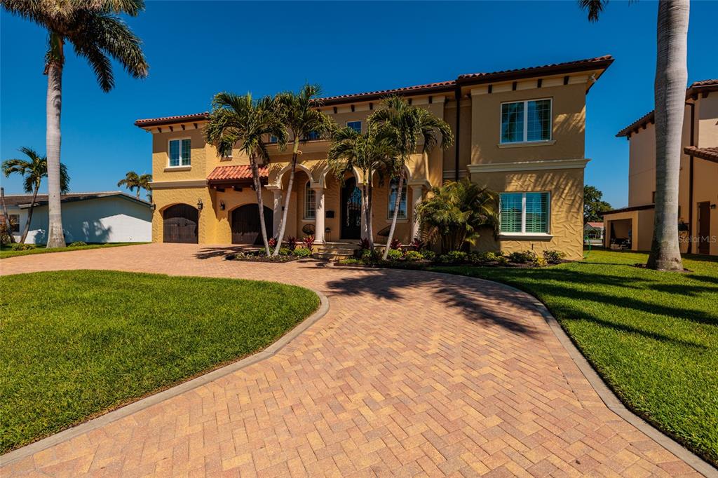 A two-story Mediterranean-style house with a brick driveway and palm trees in the front yard — 1976 KANSAS AVENUE NE, ST PETERSBURG, FL