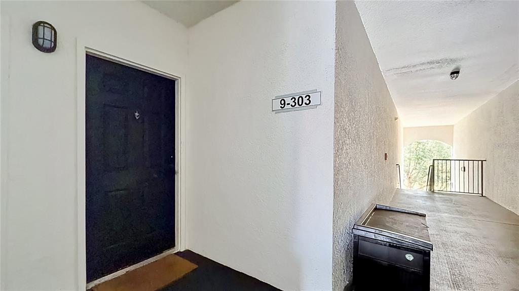 An exterior view of an apartment entrance with a black door labeled 9-303 — 2615 MAITLAND CROSSING WAY UNIT 303, ORLANDO, FL