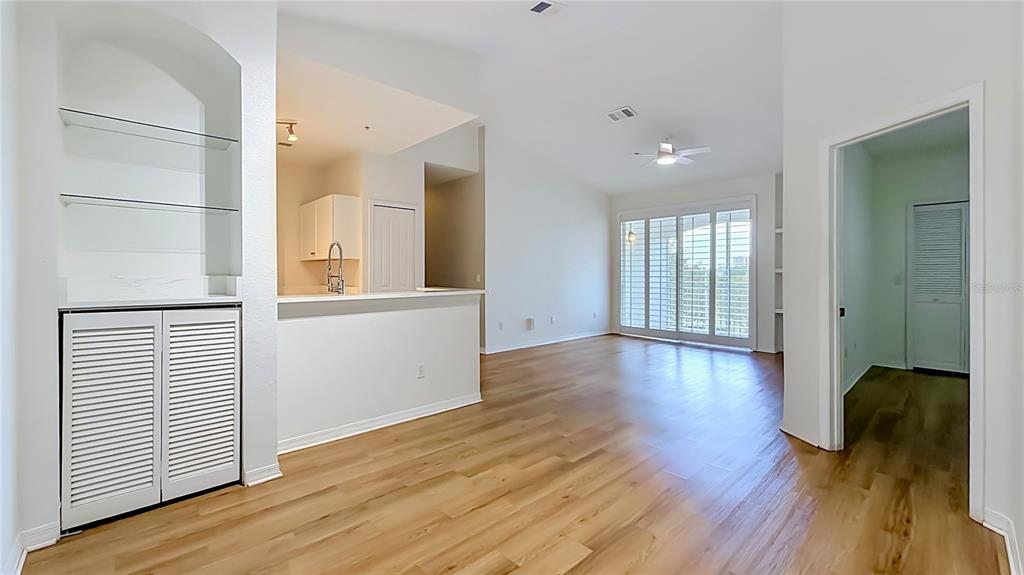 A living area with light wood floors, a kitchen pass-through, and glass sliding doors — 2615 MAITLAND CROSSING WAY UNIT 303, ORLANDO, FL