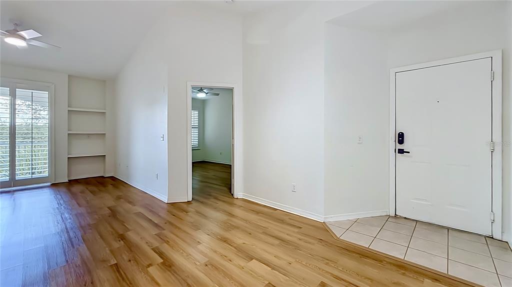 An interior view shows a living area with wood flooring, built-in shelves, and an entryway — 2615 MAITLAND CROSSING WAY UNIT 303, ORLANDO, FL
