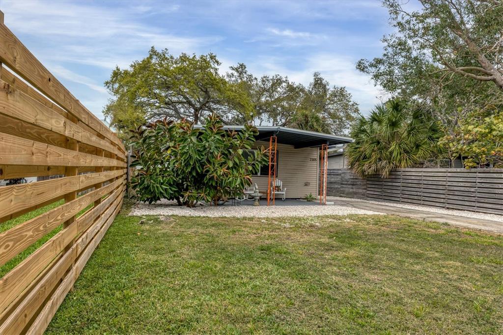 A small house with a covered porch sits behind a large bush and wooden fences — 2305 NOVUS STREET, SARASOTA, FL