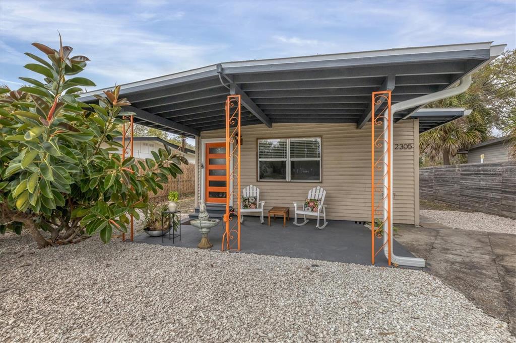 A tan house with a covered porch, orange metal supports, and a bright orange front door — 2305 NOVUS STREET, SARASOTA, FL
