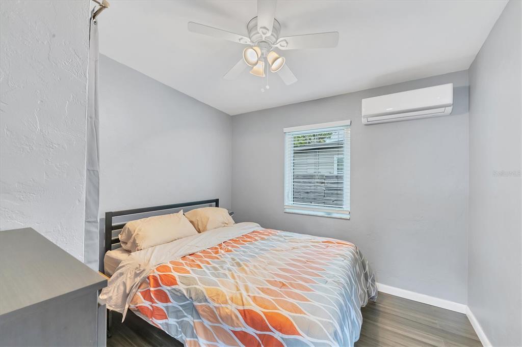 A bedroom with gray walls, a ceiling fan, a window, and a wall-mounted air conditioner — 2305 NOVUS STREET, SARASOTA, FL