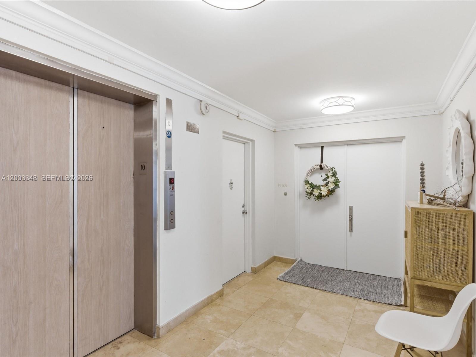 A hallway features a wood-paneled elevator, a white door, double entry doors, and tile flooring — 600 Grapetree Dr, Key Biscayne FL 33149, KEY BISCAYNE, FL