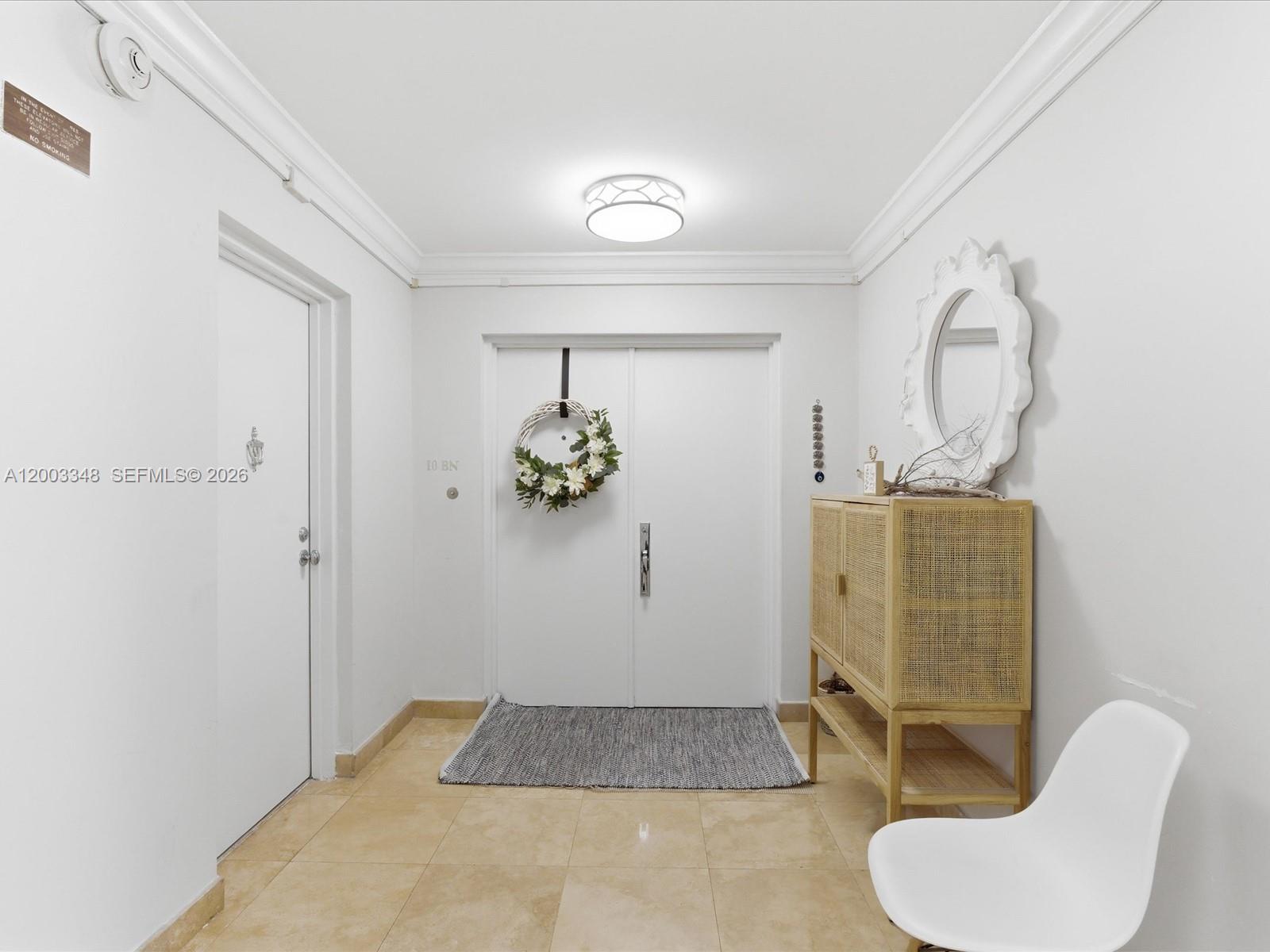 A bright entryway features white walls, tile floors, double doors with a wreath, and furniture — 600 Grapetree Dr, Key Biscayne FL 33149, KEY BISCAYNE, FL