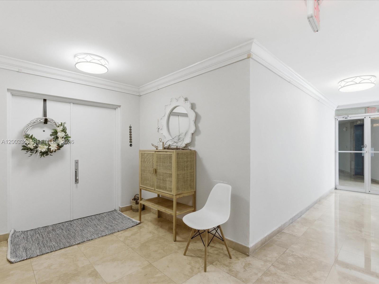 A bright entryway features a white door with a wreath, a cabinet, and a chair — 600 Grapetree Dr, Key Biscayne FL 33149, KEY BISCAYNE, FL