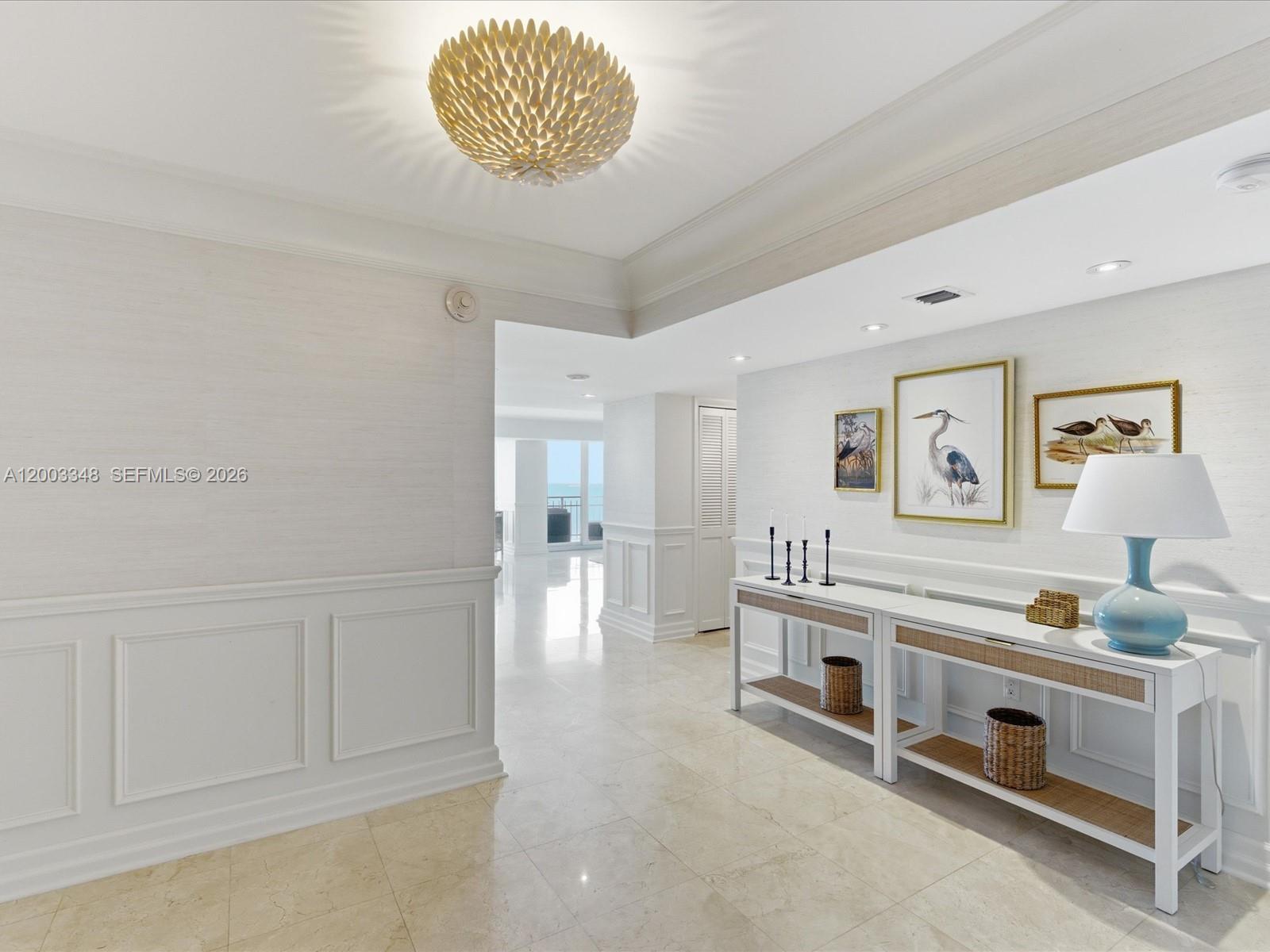 A bright hallway features white wainscoting, a textured wall covering, and a decorative ceiling fixture — 600 Grapetree Dr, Key Biscayne FL 33149, KEY BISCAYNE, FL