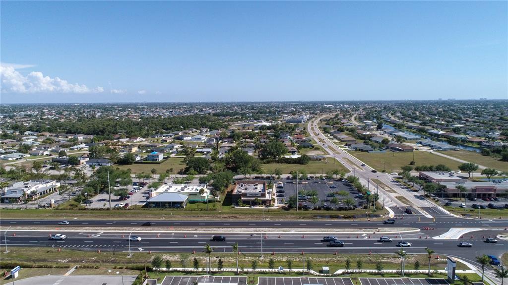 An aerial view shows a multi-lane road, commercial parking lots, and surrounding residential neighborhoods — 758 SW 4TH STREET, CAPE CORAL, FL
