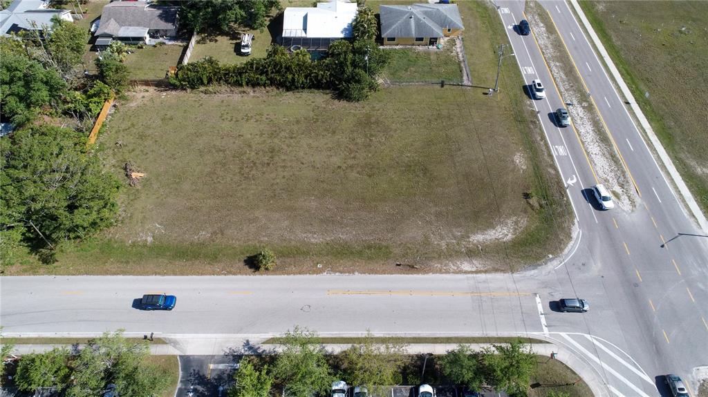 An aerial view shows a vacant, grassy rectangular lot situated between a road and houses — 758 SW 4TH STREET, CAPE CORAL, FL