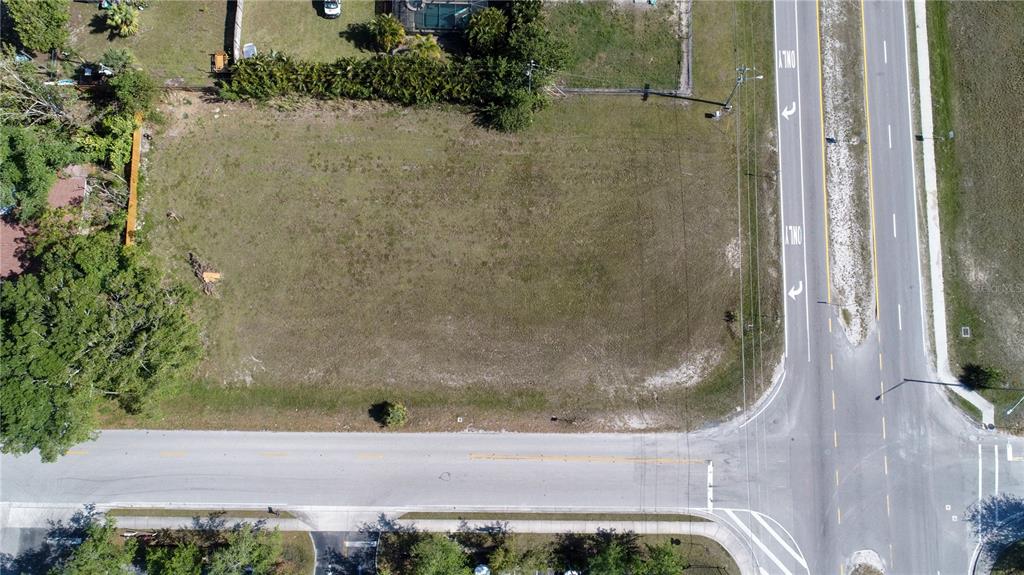 An aerial view shows a vacant, rectangular grassy lot situated at a road intersection — 758 SW 4TH STREET, CAPE CORAL, FL
