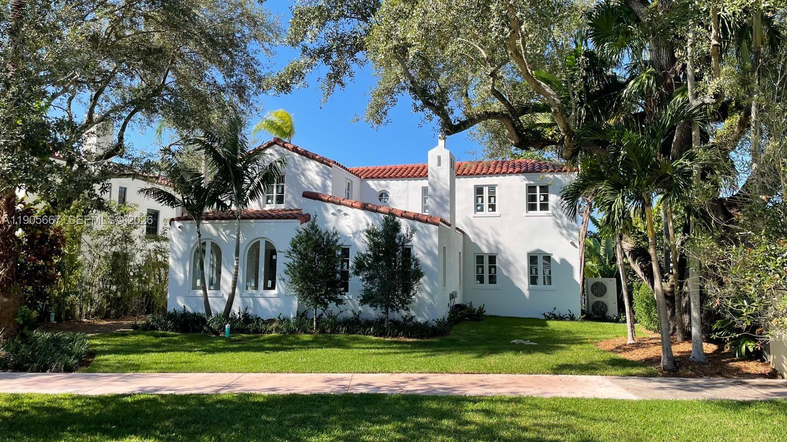 A two-story white stucco house with a red tile roof sits behind a green lawn — 4100 Monserrate St, Coral Gables FL 33146, CORAL GABLES, FL