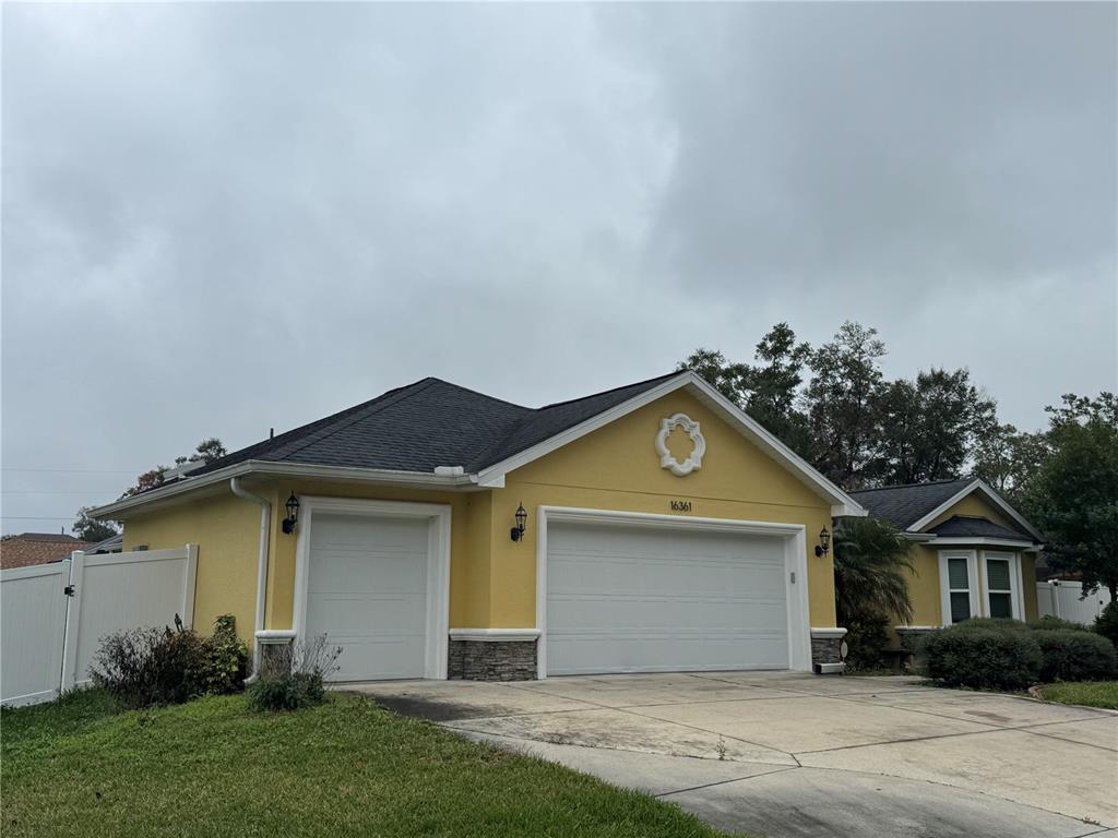 A yellow house with a two-car garage and a single-car garage under a dark roof — 16361 SE 80TH TERRACE, SUMMERFIELD, FL