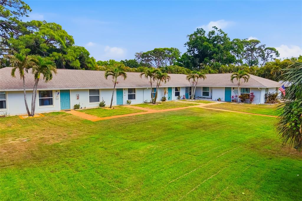 A single-story building with a long stone walkway leading to multiple blue entry doors — 4001 GROVELAND AVENUE, SARASOTA, FL