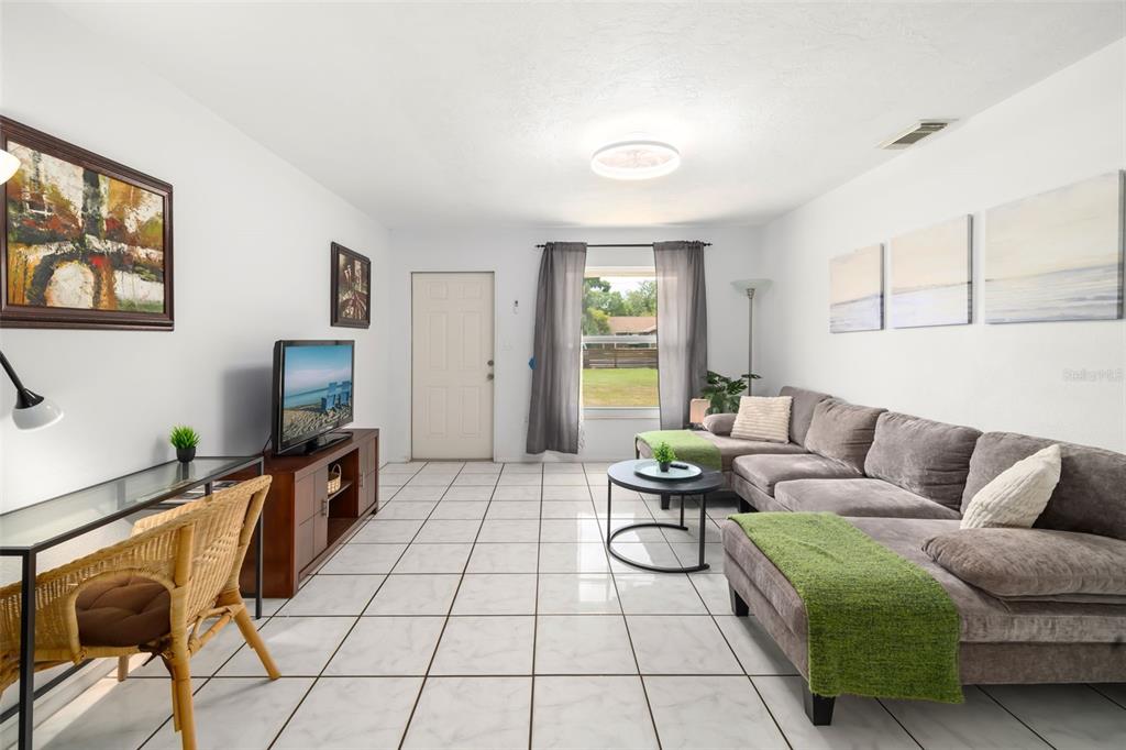 A living room features white tile flooring, a gray sectional sofa, and a television console — 4001 GROVELAND AVENUE, SARASOTA, FL