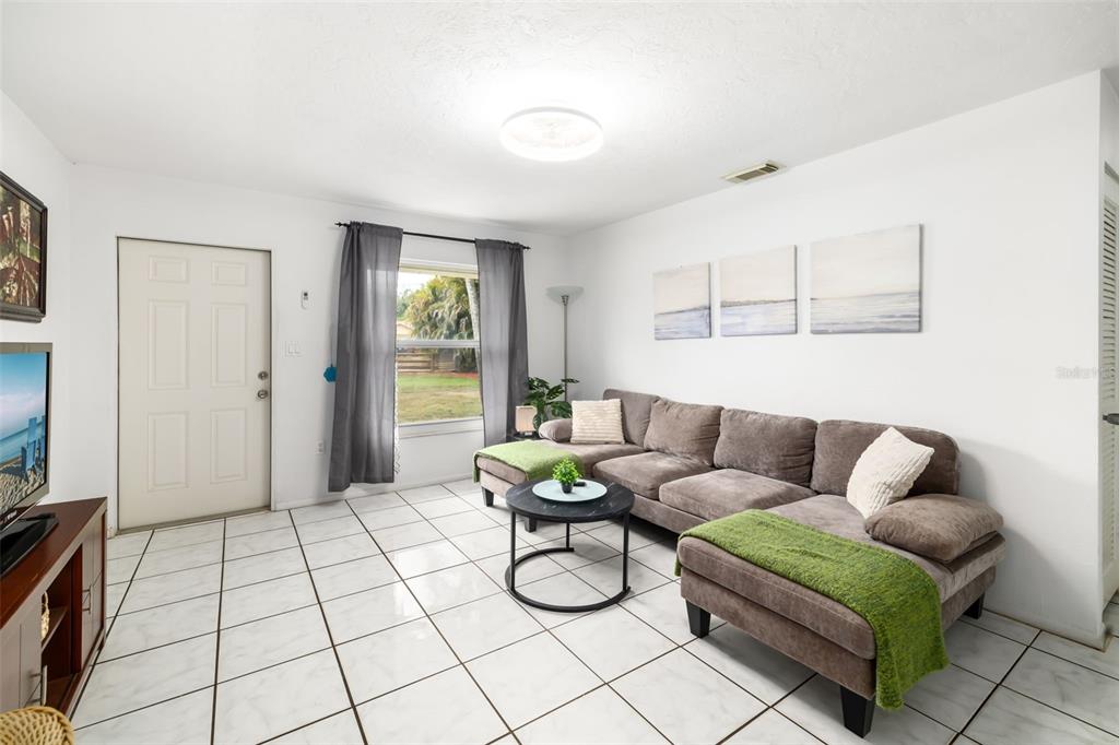 A living room features white tile floors, a television on a wooden stand, and furniture — 4001 GROVELAND AVENUE, SARASOTA, FL
