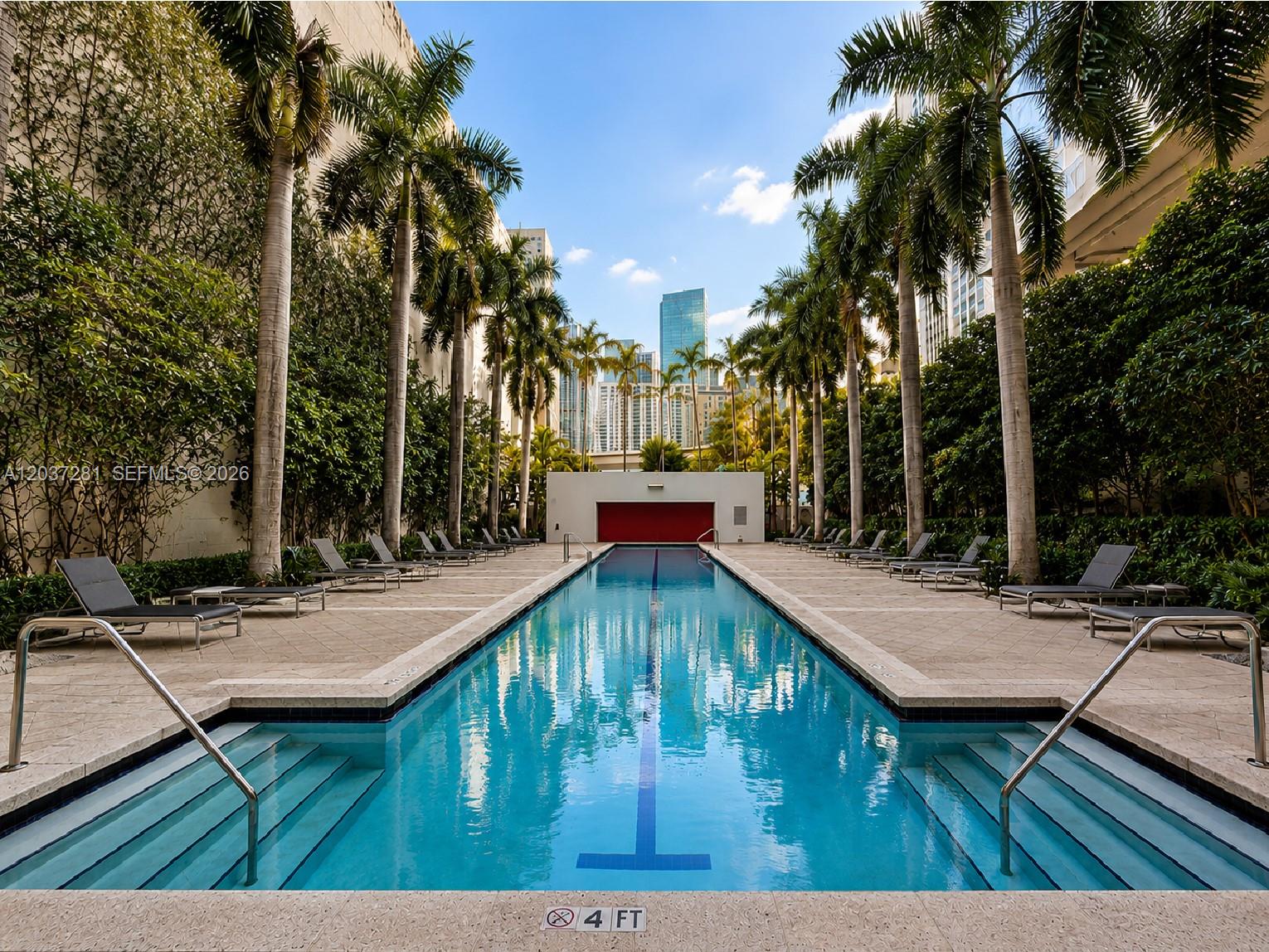 A long, narrow outdoor swimming pool is surrounded by palm trees and lounge chairs — 133 NE 2nd Ave # 1508, Miami FL 33132, MIAMI, FL