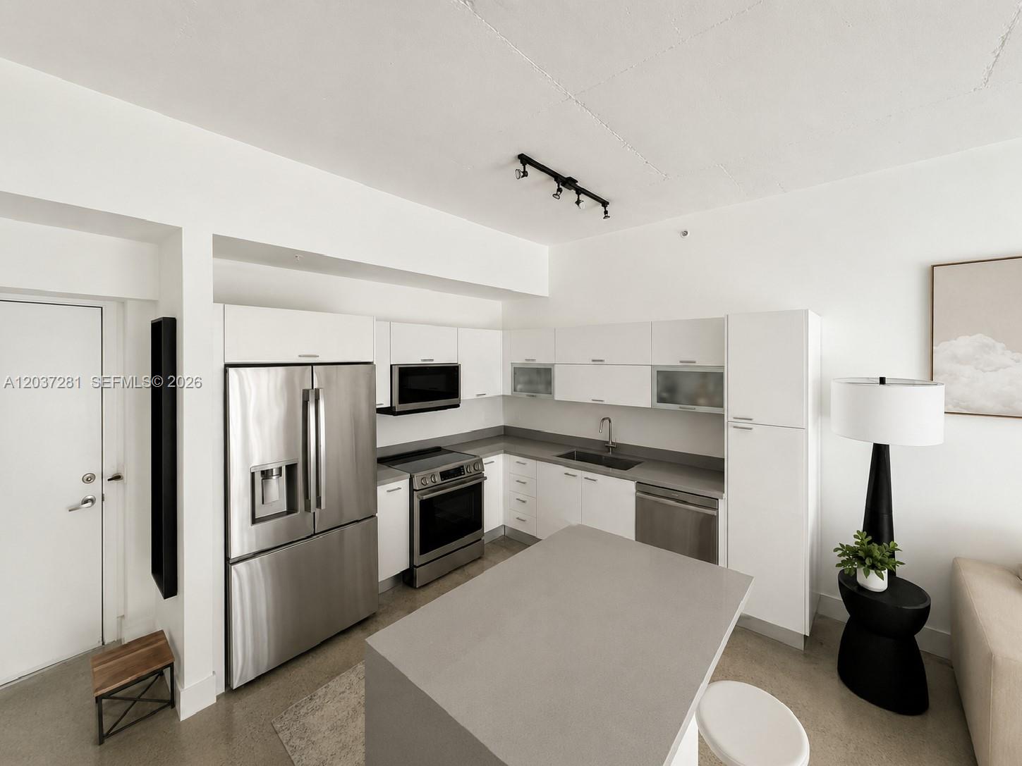 A modern kitchen features white cabinetry, stainless steel appliances, and a gray stone island — 133 NE 2nd Ave # 1508, Miami FL 33132, MIAMI, FL