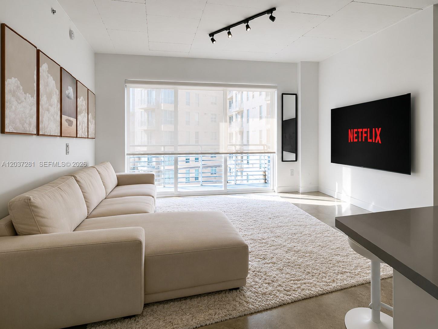 A modern living room features a beige sectional sofa, a large rug, and a wall-mounted television — 133 NE 2nd Ave # 1508, Miami FL 33132, MIAMI, FL