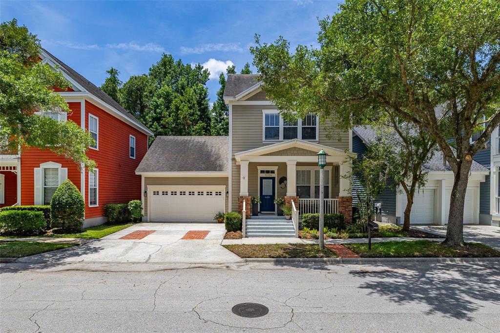 A two-story tan house with a front porch, attached garage, and a red house adjacent — 1024 BANKS ROSE STREET, CELEBRATION, FL