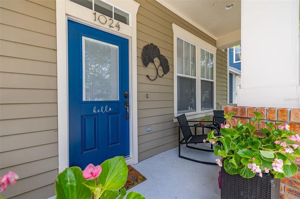 A blue front door with a hello sign sits on a porch with rocking chairs — 1024 BANKS ROSE STREET, CELEBRATION, FL