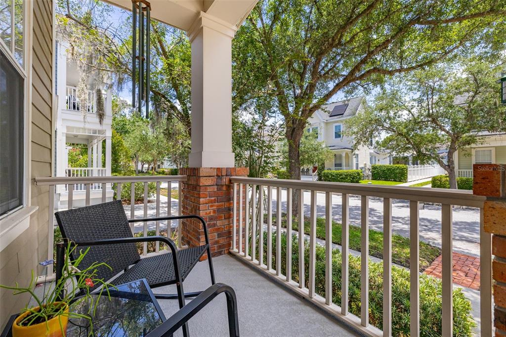 A covered porch features a brick-based column, white railing, and a view of neighborhood houses — 1024 BANKS ROSE STREET, CELEBRATION, FL