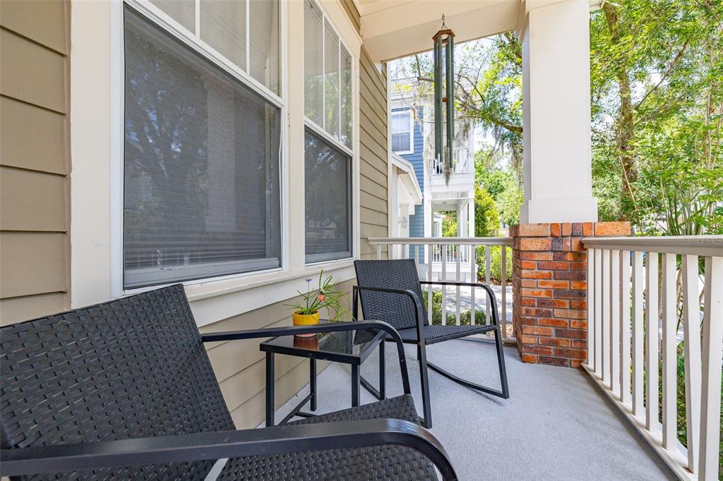 A covered porch features two black wicker chairs, a small side table, and white railings — 1024 BANKS ROSE STREET, CELEBRATION, FL