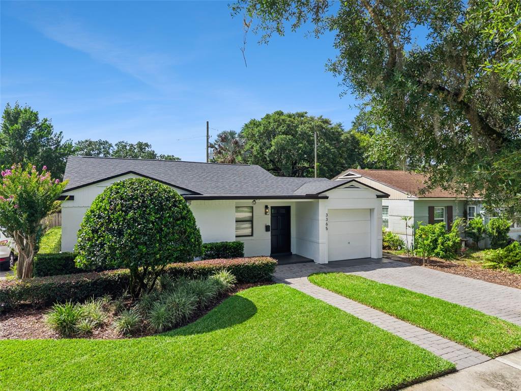 A white single-story house with a black front door, a garage, and a landscaped yard — 3365 PELHAM ROAD, ORLANDO, FL