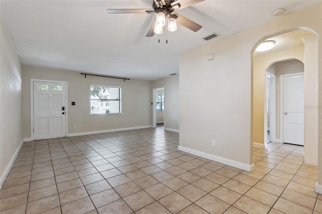 A living room features beige tile flooring, a ceiling fan, and an arched entryway — 3365 PELHAM ROAD, ORLANDO, FL