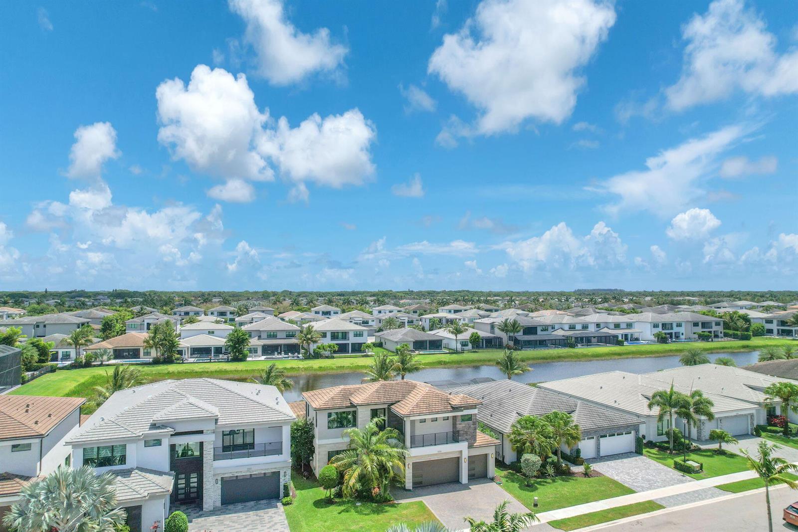 An aerial view shows several modern suburban houses with tiled roofs near a small lake — 8586 Dream Falls Street, Boca Raton FL 33496, BOCA RATON, FL