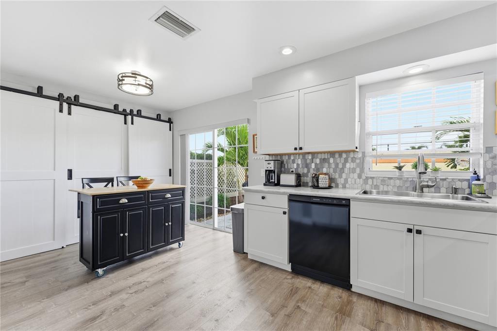 A kitchen features white cabinets, a black rolling island, stainless steel appliances, and sliding doors — 3625 57TH AVENUE DRIVE W UNIT 43, BRADENTON, FL