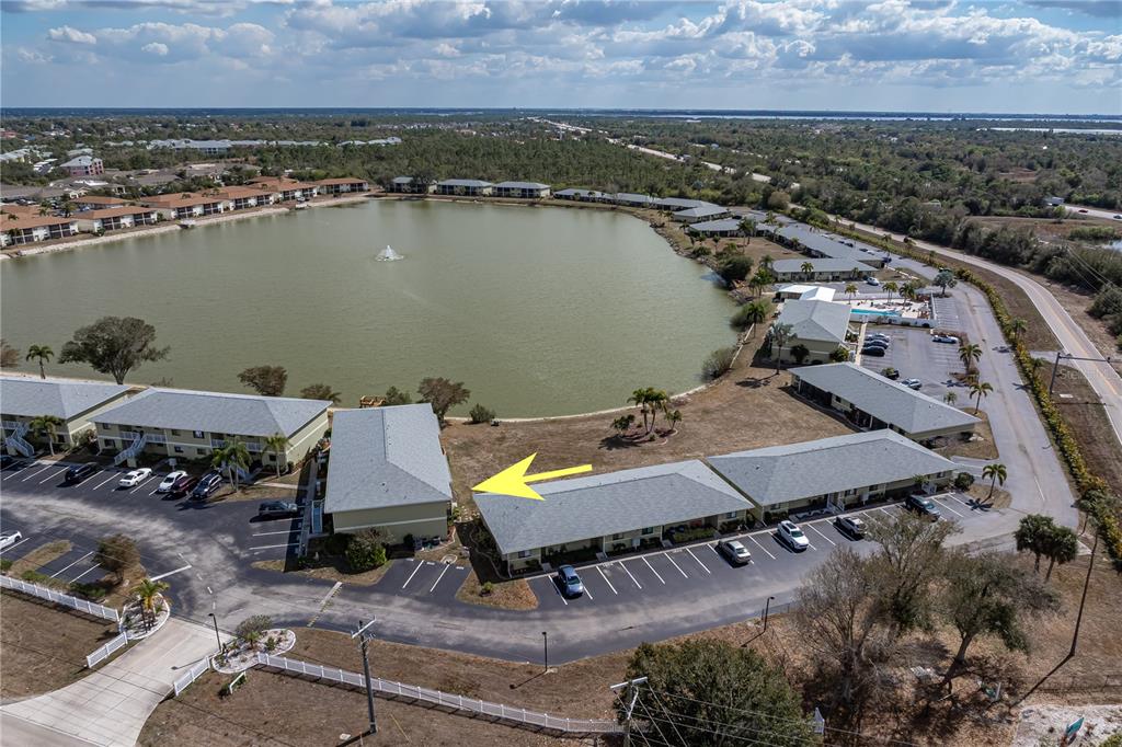 An aerial view shows apartment buildings surrounding a lake with a central fountain — 25225 RAMPART BOULEVARD UNIT 1606, PUNTA GORDA, FL