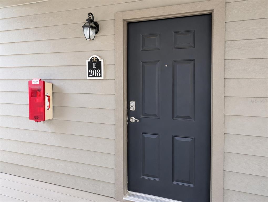 A dark grey door with a keypad lock is next to a red fire alarm — 2500 WINDING CREEK BOULEVARD UNIT E208, CLEARWATER, FL