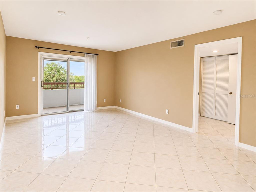 An empty room with beige walls, tile flooring, a sliding glass door, and a closet — 2323 FEATHER SOUND DRIVE UNIT 205, CLEARWATER, FL