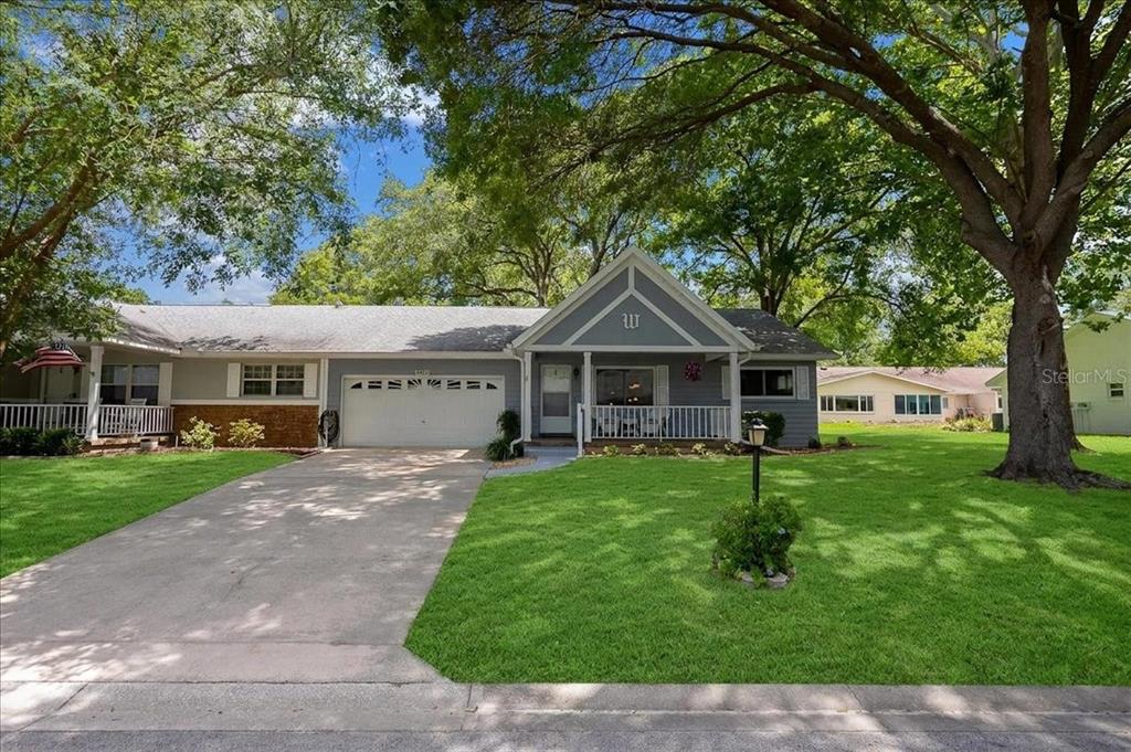 A single-story gray house with a white garage door, front porch, and large shade trees — 8889 SW 96TH STREET UNIT F, OCALA, FL