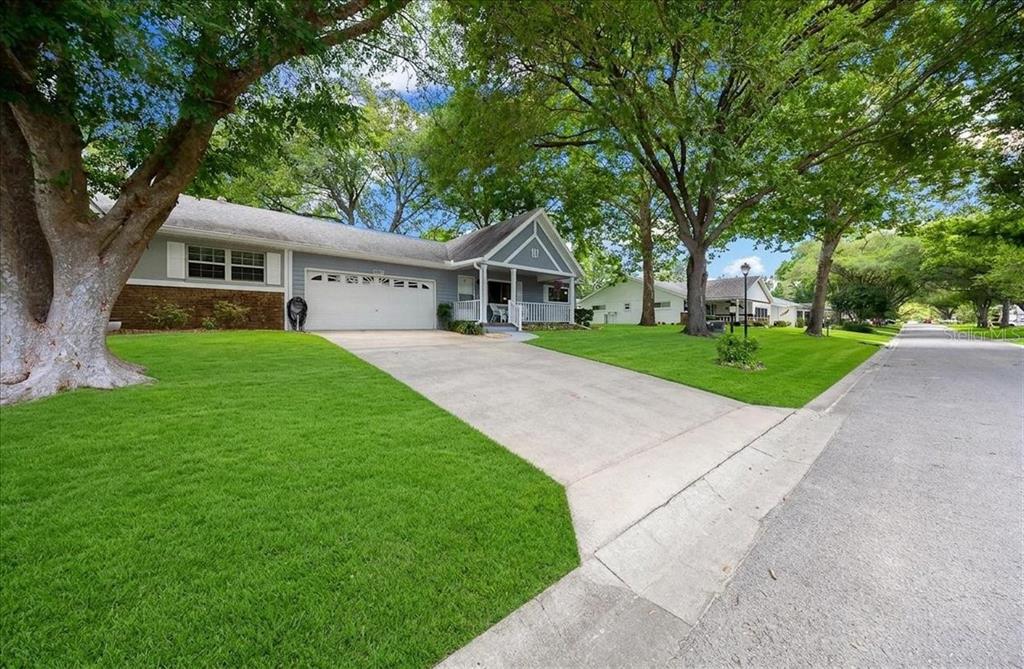 A single-story house with a white garage, a concrete driveway, and large trees in front — 8889 SW 96TH STREET UNIT F, OCALA, FL