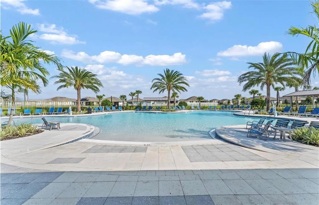 A swimming pool with palm trees and lounge chairs on a sunny day — 1817 WALNUT CREEK DRIVE, KISSIMMEE, FL