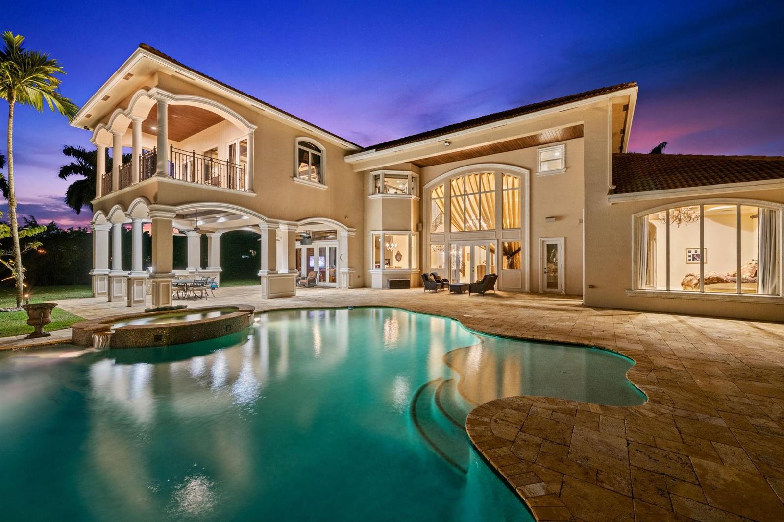 A two-story house with a pool, covered patio, and large arched windows at dusk — 12741 Kapok Lane, Davie FL 33330, DAVIE, FL
