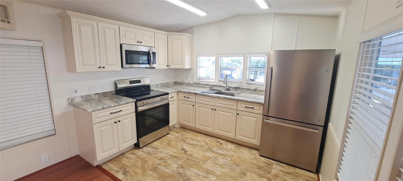 A kitchen with cream cabinets, stainless steel appliances, and a marble-patterned countertop — 5362 SE 65th Avenue, Okeechobee FL 34974, OKEECHOBEE, FL